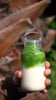 KINTO small clear plastic water bottle with matcha latte inside being shaken in slow motion.